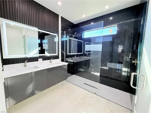 Full bath featuring double vanity, a marble finish shower, and recessed lighting