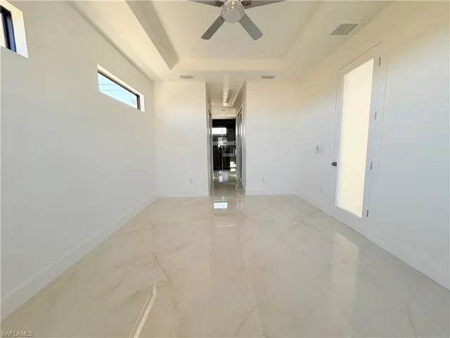 Unfurnished room with a ceiling fan and a tray ceiling