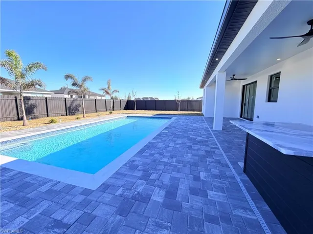 View of swimming pool with patio surround, a fenced backyard, and a hot tub