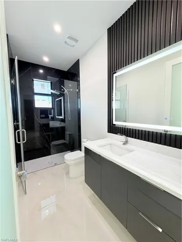 Bathroom featuring vanity, a marble finish shower, and recessed lighting