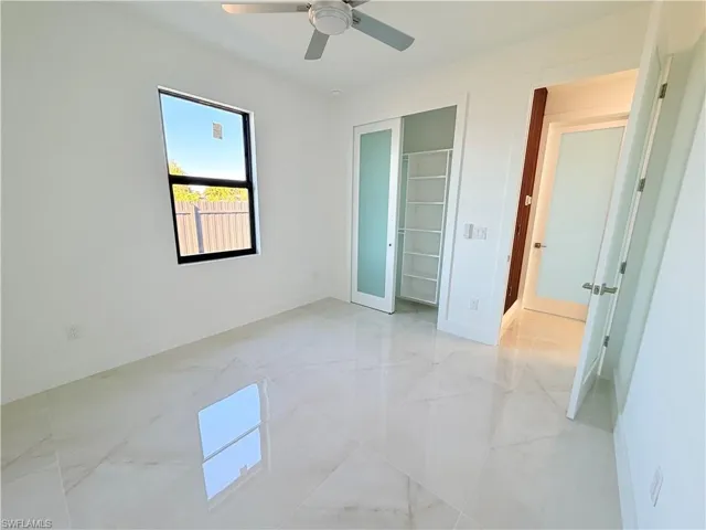 Unfurnished bedroom featuring ceiling fan, light marble finish flooring, and a closet
