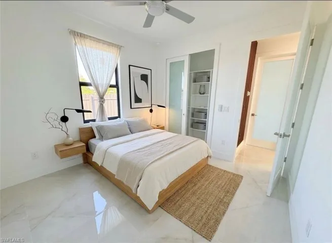 Bedroom with a ceiling fan and light marble finish flooring