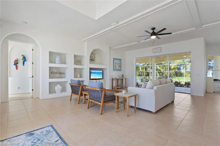 Living area with built in features, beam ceiling, light tile patterned flooring, ceiling fan, and coffered ceiling