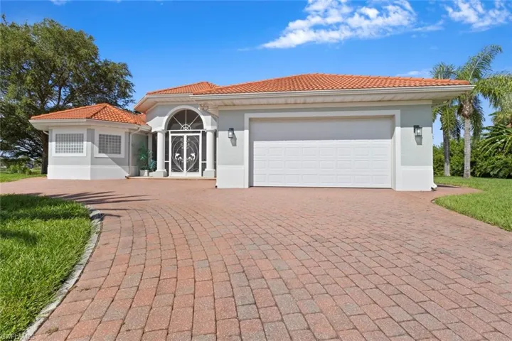 Mediterranean / spanish house with an attached garage, stucco siding, decorative driveway, and a tile roof