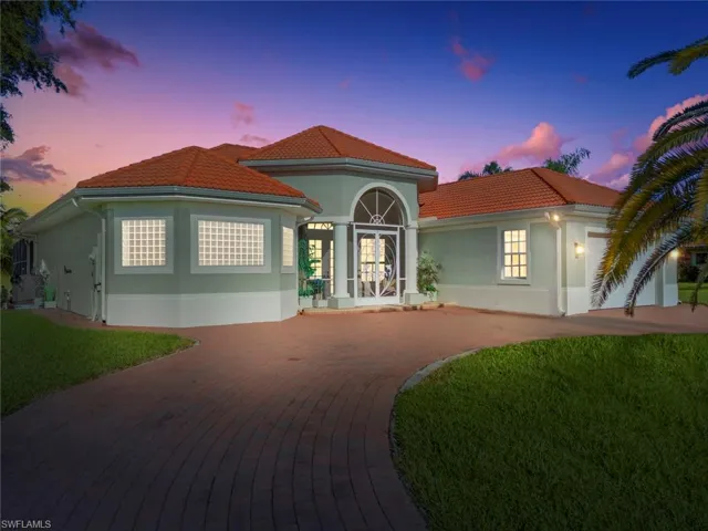 Mediterranean / spanish home featuring a lawn, stucco siding, curved driveway, and a tiled roof