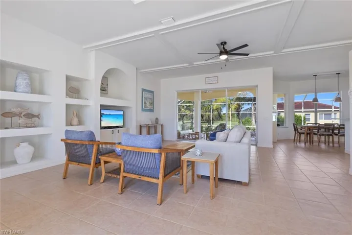 Living room featuring built in features, light tile patterned floors, plenty of natural light, ceiling fan, and beamed ceiling