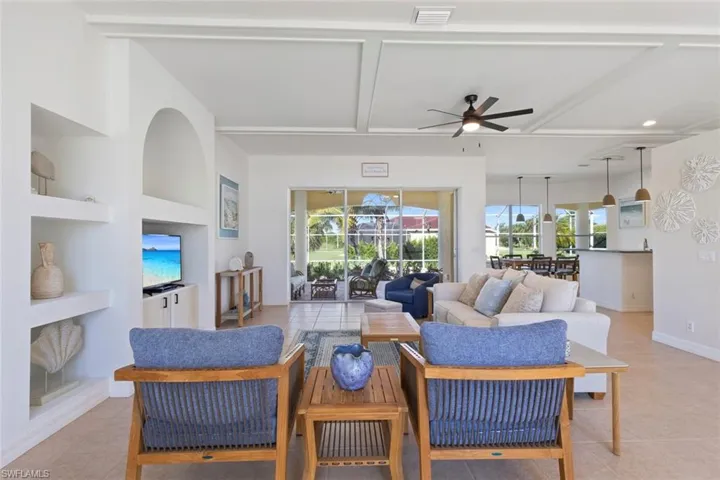 Living area featuring light tile patterned flooring, built in features, beam ceiling, a ceiling fan, and recessed lighting