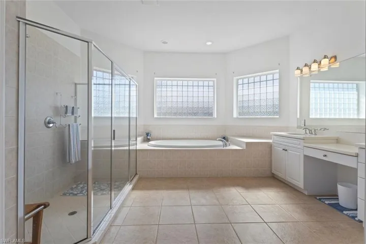 Bathroom with a bath, vanity, a shower stall, light tile patterned floors, and recessed lighting