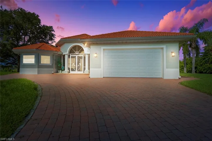 Mediterranean / spanish house with an attached garage, stucco siding, a tile roof, decorative driveway, and french doors