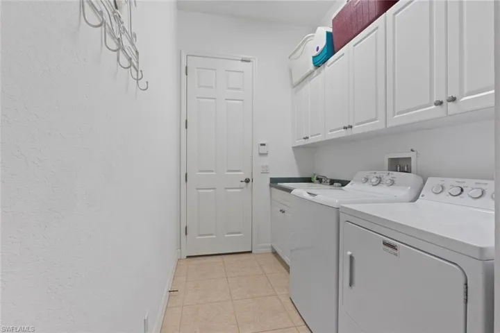 Laundry area featuring light tile patterned flooring, cabinet space, and washer and dryer