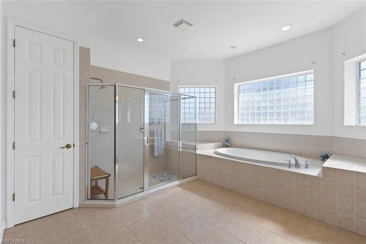 Bathroom featuring a garden tub, a shower stall, light tile patterned flooring, and recessed lighting