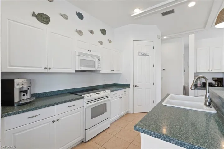 Kitchen featuring white cabinetry, white appliances, light tile patterned flooring, and recessed lighting