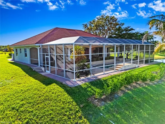 Rear view of house with a sunroom, a yard, a tiled roof, a swimming pool, and a lanai