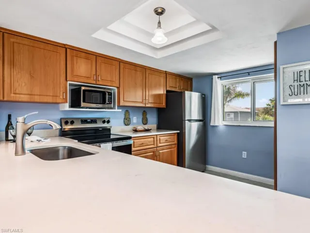 Kitchen with pendant lighting, sink, stainless steel appliances, and a raised ceiling