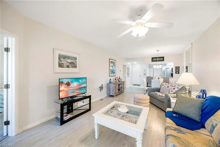 Living area featuring light wood-style floors, ceiling fan, baseboards, and a chandelier