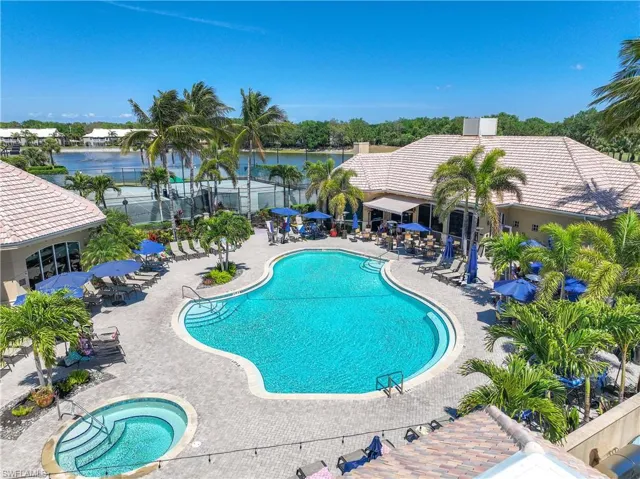 Community pool with a patio area, a water view, and fence
