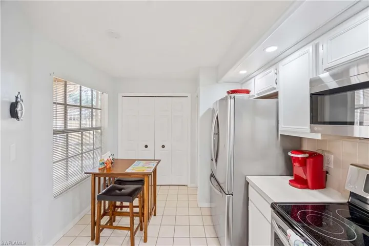 Kitchen with appliances with stainless steel finishes, light countertops, white cabinets, light tile patterned floors, and baseboards