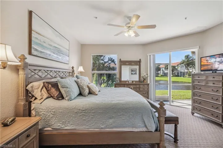 Carpeted main bedroom with multiple windows, access to outside, and ceiling fan