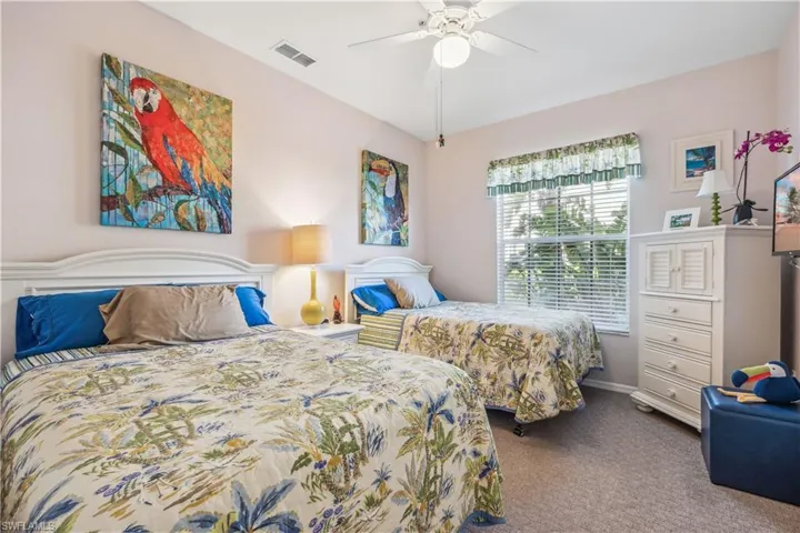 Carpeted guest  bedroom with ceiling fan.