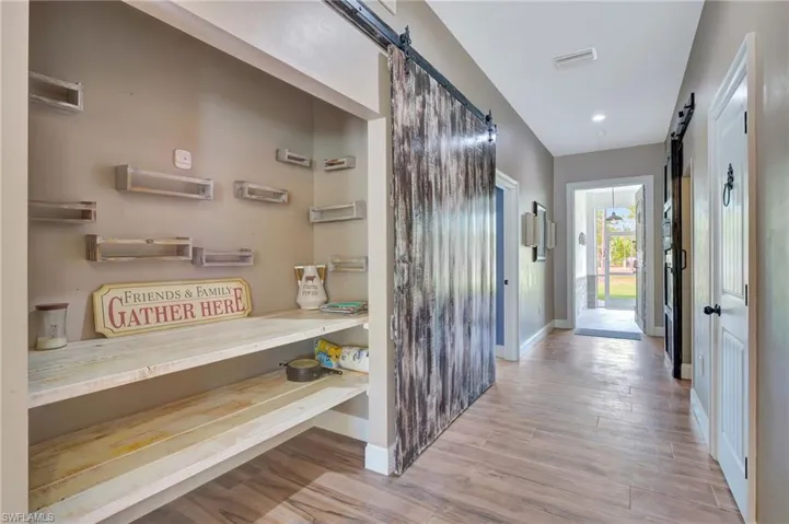 Hall with a barn door and porcelain tile floors