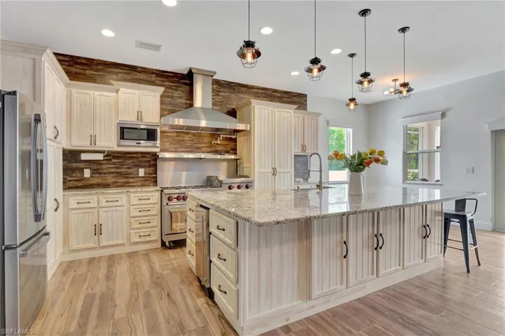 Kitchen with large island, Gas 6 burner stove, decorative light fixtures, decorative backsplash, Lots of Cabinets and storage