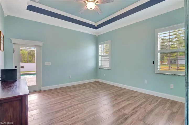 Primary Bedroom featuring a raised ceiling, crown molding and access to out door area and Pool