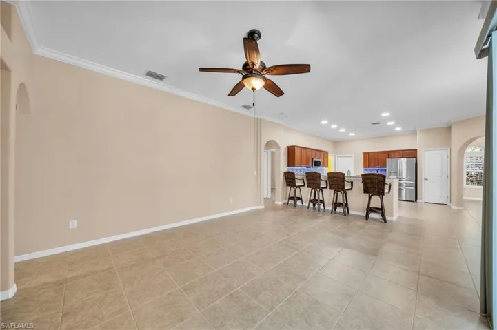 Living area with arched walkways, ornamental molding, light tile patterned flooring, recessed lighting, and ceiling fan