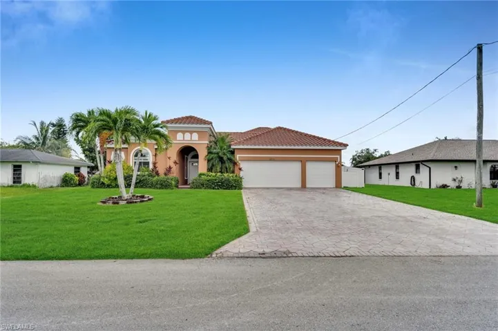 Mediterranean / spanish house with a front lawn, an attached garage, stucco siding, decorative driveway, and a tiled roof