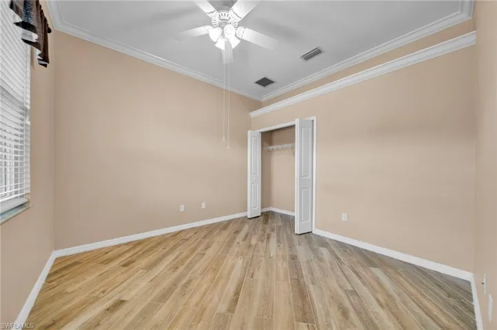 Unfurnished bedroom featuring crown molding, light wood finished floors, a ceiling fan, and a closet