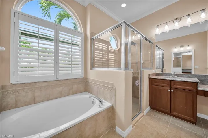 Full bathroom featuring vanity, a bath, a stall shower, light tile patterned floors, and crown molding