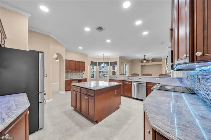 Kitchen with tasteful backsplash, appliances with stainless steel finishes, a kitchen island, recessed lighting, and a peninsula