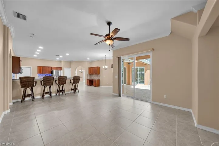 Living room with ceiling fan, ornamental molding, light tile patterned floors, recessed lighting, and a chandelier