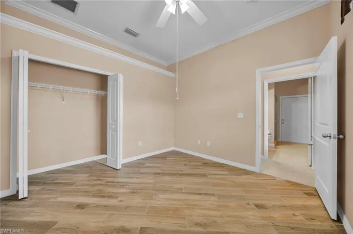 Unfurnished bedroom with crown molding, wood tiled floors, a ceiling fan, and a closet