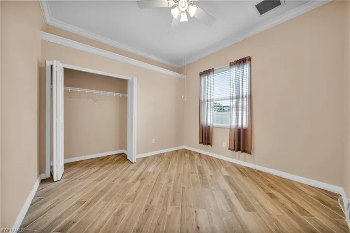 Unfurnished bedroom with ornamental molding, light wood-style flooring, ceiling fan, and a closet
