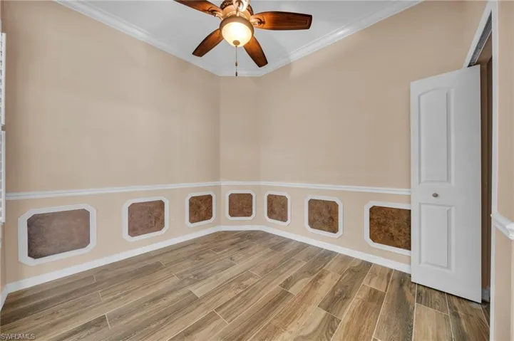 Spare room featuring crown molding, wood tiled floors, and ceiling fan