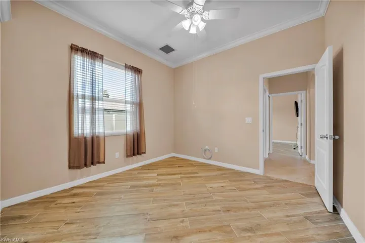 Spare room with crown molding, wood tiled floors, and ceiling fan