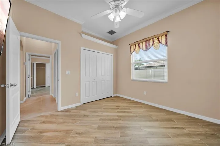 Unfurnished bedroom featuring ornamental molding, wood tiled floors, ceiling fan, and a closet