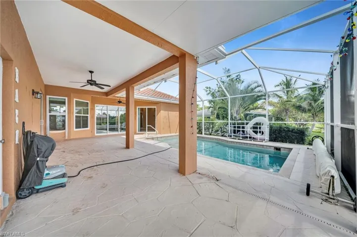Swimming pool featuring a patio, a sunroom, ceiling fan, and glass enclosure