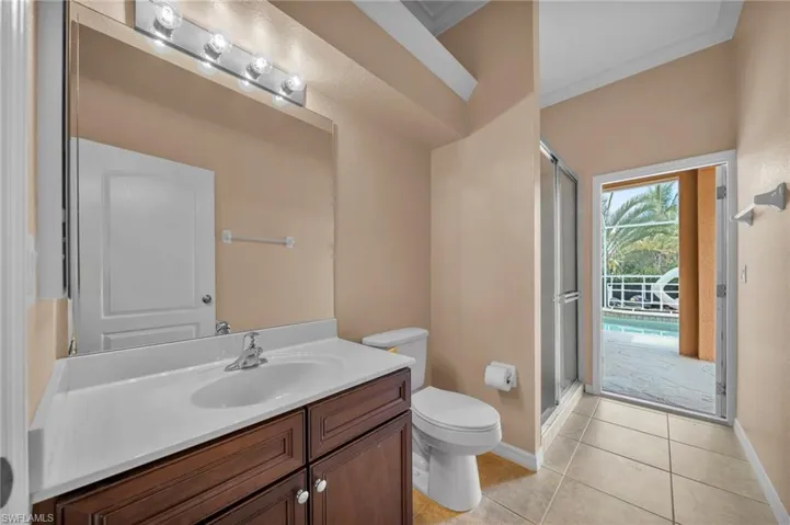 Full bath with vanity, light tile patterned flooring, a stall shower, and ornamental molding