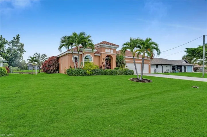 Mediterranean / spanish house with driveway, a front lawn, stucco siding, a tile roof, and a garage
