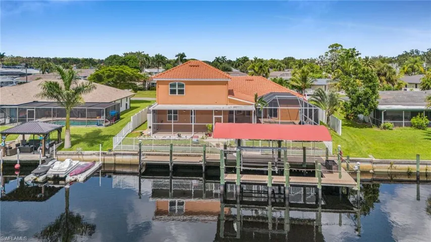 Dock with boat lift, glass enclosure, a fenced backyard, a water view, and a residential view