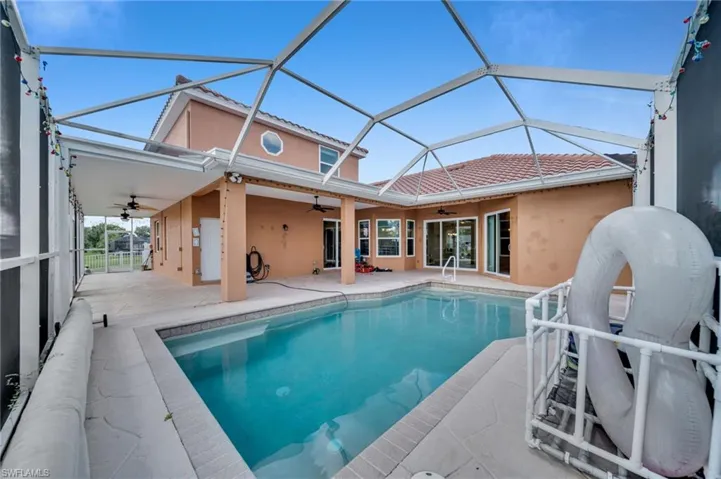 Rear view of house featuring a sunroom, a patio, an outdoor pool, a ceiling fan, and stucco siding