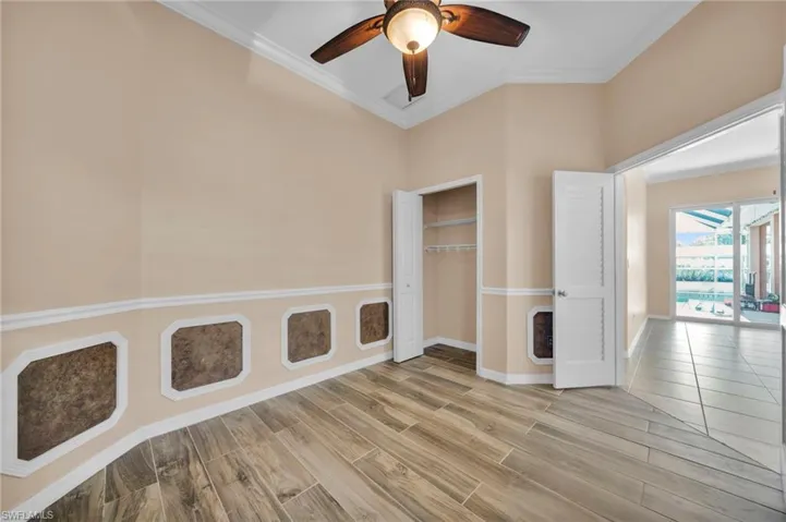 Unfurnished bedroom featuring crown molding, a closet, a ceiling fan, and light wood finished floors