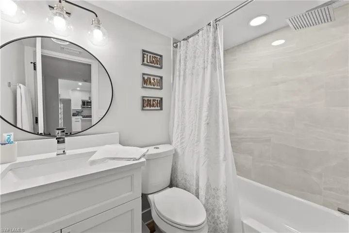 Bathroom featuring recessed lighting, shower / bathtub combination with curtain, and vanity