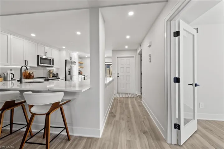 Kitchen featuring a kitchen bar, recessed lighting, a peninsula, white cabinetry, and light stone countertops