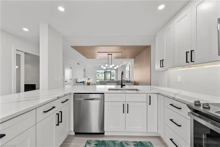 Kitchen with white cabinetry, a chandelier, light stone counters, open floor plan, and recessed lighting