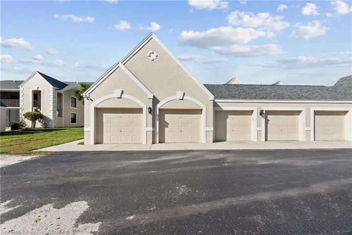 View of front of property featuring stucco siding, community garages, and a shingled roof