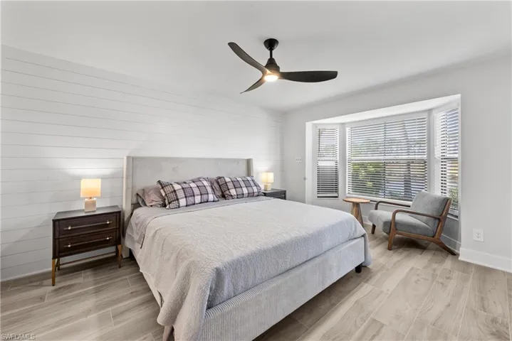 Bedroom with wood tiled floors, a ceiling fan, and wood walls