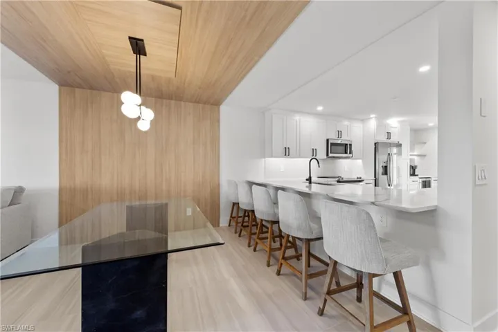 Kitchen with wood ceiling, white cabinets, a peninsula, a kitchen breakfast bar, and stainless steel appliances