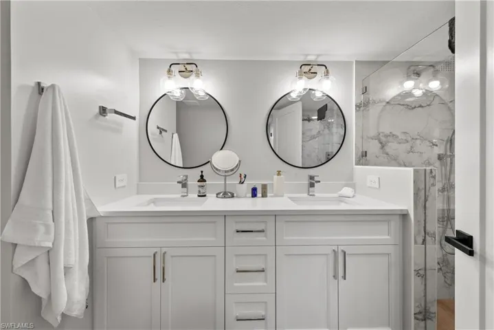 Bathroom with a marble finish shower and double vanity